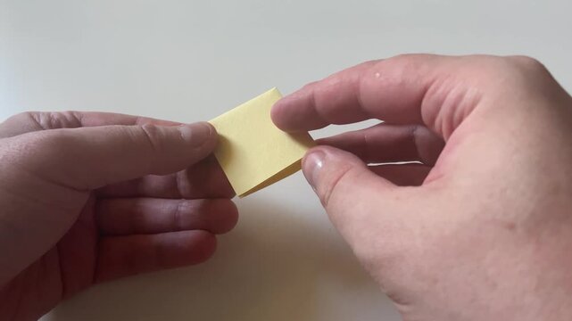 Hands Unfolding Small Yellow Square Sticky Note Paper Close Up