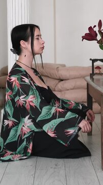 Vertical video. Spiritual relaxation. Mind tranquility. Woman cross-legged practicing calming yoga enjoying aromatherapy meditation with candles indoor.