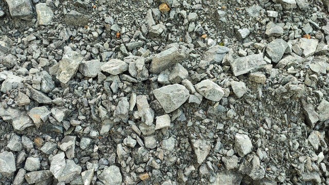 High-angle texture background of grey crushed stones and granite rock fragments. Perfect natural mineral aggregate pattern for construction or design.