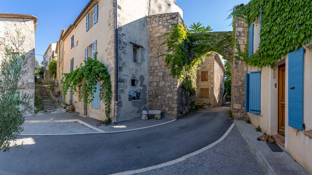 Puimoisson, France - 07 05 2026: Panoramic view of typical staircase, street, houses and medieval ramparts Gate of the hilltop village under a blue sunny sky