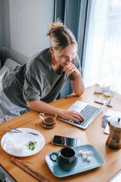 Young woman multitasking with smartphone and laptop while working remotely from home, modern Gen Z freelance lifestyle, digital communication and flexible online work.