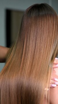 Hairstylist showing smooth, straight light brown hair after keratin chemical hair straightening. Hairdresser showing results after keratin treatment. Perfect straight hair .