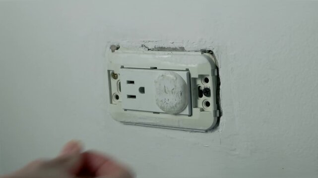 Close-up of hand installing a child safety outlet cover on an uncovered electrical wall socket, 4K 60fps video