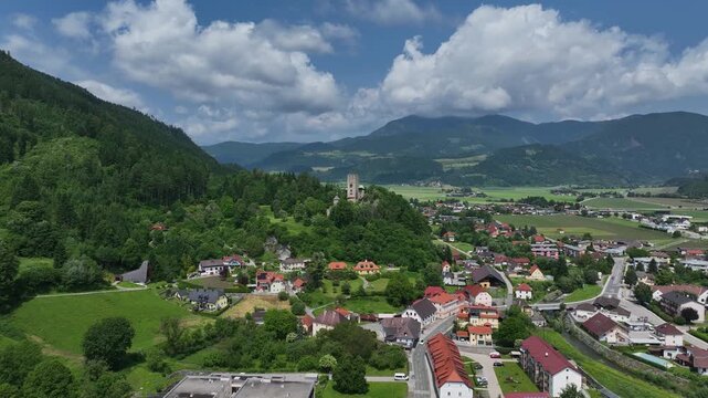 Summer drone footage showing medieval Friesach, old fortified walls, rooftops, towers, hills, serene atmosphere, warm daylight, gentle cinematic motion