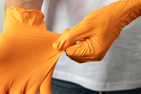 Person putting on orange protective work gloves