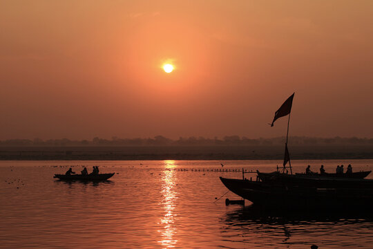 Silhouettes of passengers aboard wooden boats at sunrise on the Ganges River in Varanasi, India