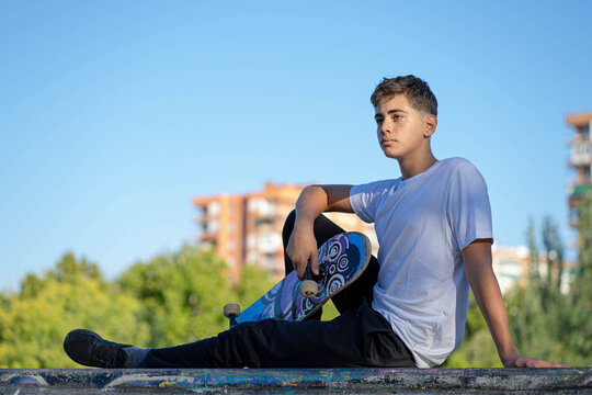 Boy sitting with skateboard in hands
