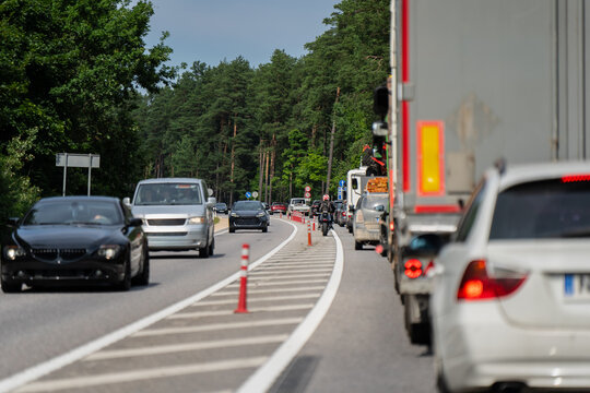 Automobile congestion, freight transport trucks, and commuter cars driving slowly along a bottlenecked regional route during lane division