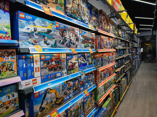 Fototapeta premium DNIPRO, UKRAINE - JULY 21, 2026: Perspective view of a long supermarket shelf packed with Lego City construction toy sets. Brightly lit aisle with numerous plastic building kits.