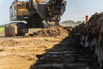 Fototapeta premium Industrial earthmoving vehicle performing precise excavation work and site preparation on a dirt roadbed construction site