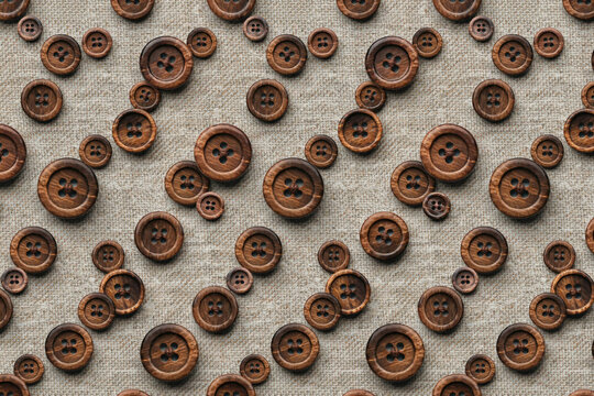 Seamless pattern of round wooden sewing buttons arranged on a textured light beige linen fabric background, rustic craft supply wallpaper
