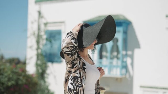 Smiling woman in hat and sunglasses at Sidi Bou Said, Tunisia