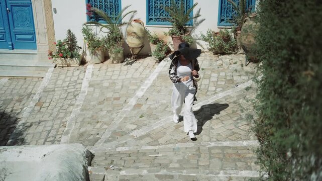 Aerial view of woman running up stone stairs in Sidi Bou Said