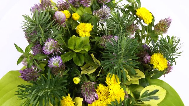 Spraying water on a flower arrangement of ornamental garden plants in a glass bowl, top view