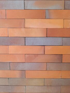 Modern brick wall with orange and gray rectangular bricks arranged in a clean horizontal pattern, ideal as an architectural background and decorative texture.