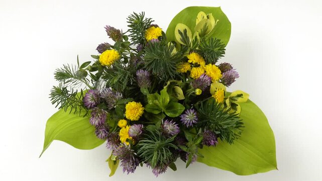 Spraying water on a flower arrangement of ornamental garden plants in a glass bowl, top view