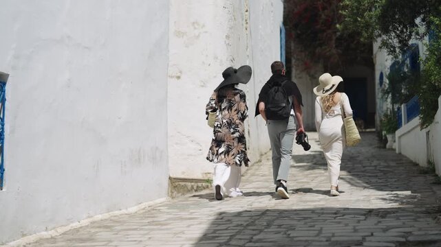 Stylish tourists walking down a white-walled street in Sidi Bou Said