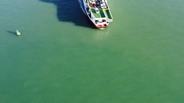 Aerial drone video of a Red Funnel ferry approaching East Cowes on the Isle of Wight, England, crossing the Solent towards the ferry terminal with panoramic coastal and waterfront views.