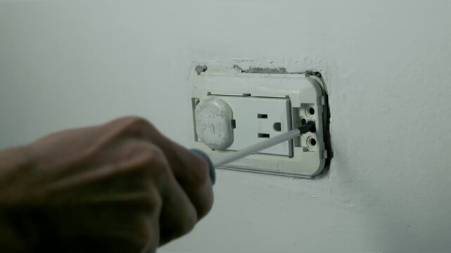 Hands Removing Screw from Uncovered Electrical Wall Outlet During Electrical Repair and Disassembly, 60fps 4K Video