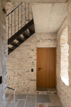 A detail of a stairwell in an old stone-built house. The staircase is modern and has been rebuilt in black steel.