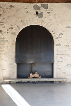 A close-up of an iron or steel fireplace, with pieces of wood inside.