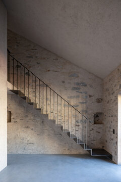 Inside a very high, empty room, and on the front wall at the far end, you can see a beautiful, large iron staircase.