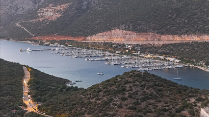 Fototapeta premium Aerial View of Kas Marina at Dusk: Yachts, Breakwater, and Coastal Lights in Turkey. 