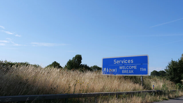 Motorway road sign, UK highway sign, British services direction sign, M6 motorway route with blue sky and dry grass on roadside