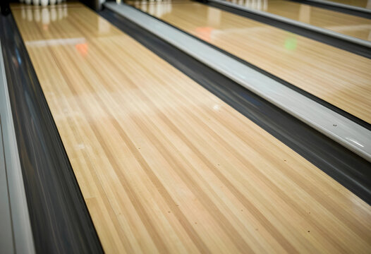 Bowling alley lane with polished wooden surface and gutters, recreational sport and entertainment activity