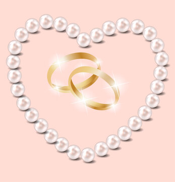 Golden wedding rings intertwined inside a pearl heart shape on a pastel pink background