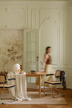 Elegant dining room interior with classic decor and a woman in motion, capturing a sophisticated ambiance and refined design
