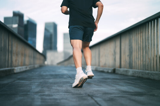 Rear view adult asian leg athlete man runner training for marathon challenge male wear sports outfit running workout exercise at outdoors urban lifestyle