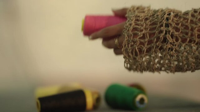 Close up of fashion student threading needle by hand preparing for detailed hand stitching work on delicate fabric