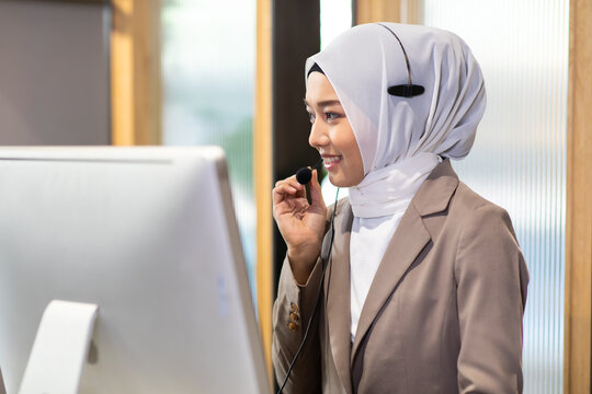 Attractive business Asian woman  muslim in suits and headsets working with desktop computer at  telemarketing customer service agents