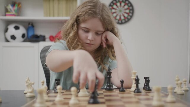 Child practicing patience during chess play. Kid playing board game for brain development. Child learning strategy skills with chess. Kid focused on winning chess position.
