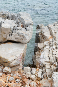 Limestone coastal rocks covered with orange lichens overlooking the Adriatic Sea on Dugi Otok, Croatia