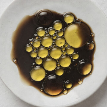 Golden Olive Oil Droplets Floating in Dark Balsamic Vinegar