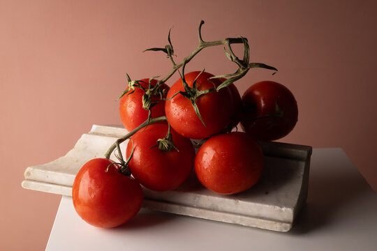 Pomodori rossi maturi a grappolo su elemento di marmo e base bianca, natura morta con spazio per il testo