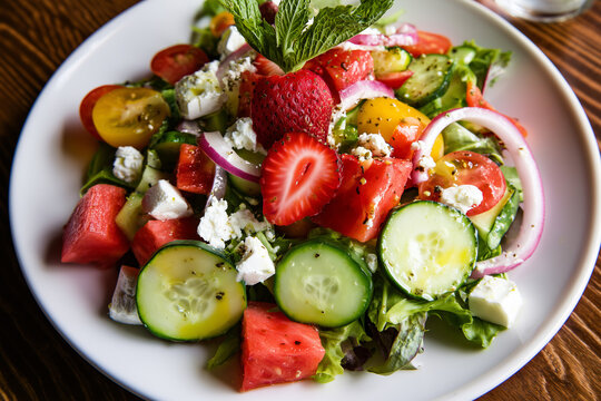 Summer salad with fresh vegetables, goat cheese, and strawberries