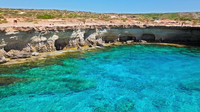 Drone view of Cape Cavo Greco coastline in Cyprus. Clear turquoise sea, curved rocky bay and pale limestone shore create a peaceful summer seascape.