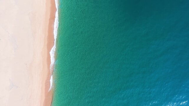 Footsteps on the sandy beach lead to the blue ocean in Bien Lo Quang. Waves crash softly against the shore under the midday sun.