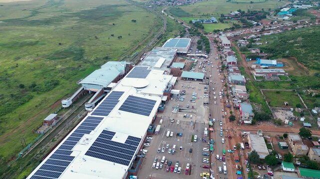 Orange Farm shopping mall roof covered in solar panels beside a crowded township street and parking lot, seen from a drone view.