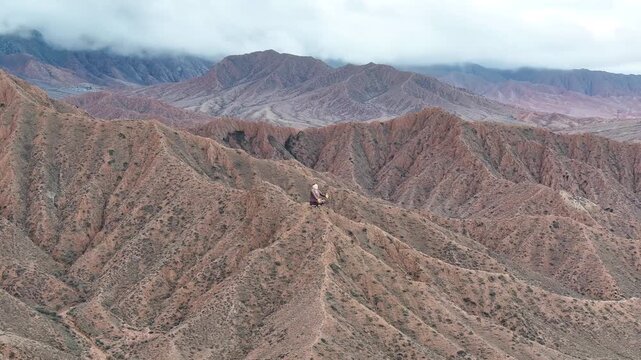 Drone flyover of Sayakbai Karalaev Statue above rugged Kyrgyzstan mountain landscape