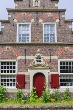 Historic brick canal house with red shutters and arched doorway in IJlst, Friesland, Netherlands