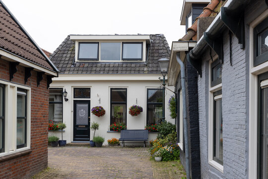 Charming courtyard house with hanging flowers and bench in IJlst, Friesland, Netherlands historic street
