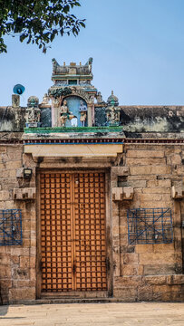 Close-up view of the entrance to Arulmigu Thirumarainatha Swamy Temple featuring a traditional brass flagstaff inside the temple complex