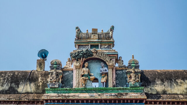 Decorative stucco sculptures depicting Hindu religious figures adorn the historic gateway of Arulmigu Thirumarainatha Swamy Temple