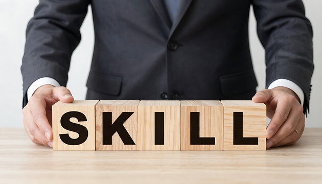 A focused professional businessman meticulously arranging colorful alphabet wooden blocks to spell the word skill on a plain white background.
