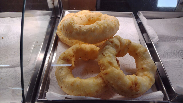 Traditional Brazilian fried cassava starch ring biscuits (biscoito de polvilho frito) displayed in a bakery showcase
