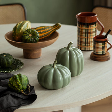 Autumn harvest display with decorative gourds and ceramic pumpkins on a table, creating a cozy fall atmosphere